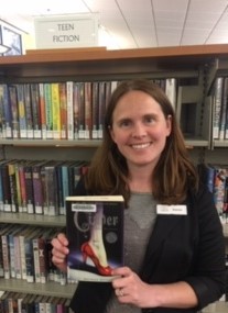 woman holding book "Cinder" by Marissa Meyer