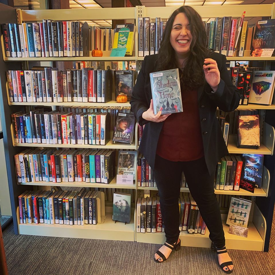 woman holding book "Shadow & Bone" by Leigh Bardugo