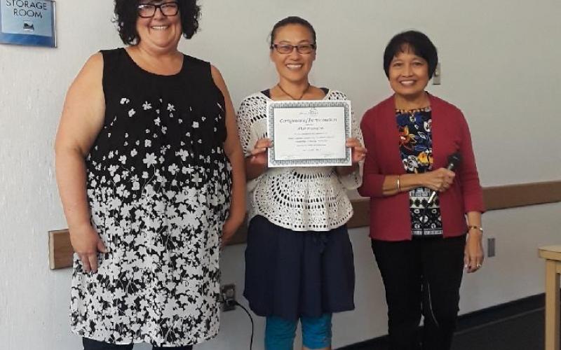 three women, one holding certificate