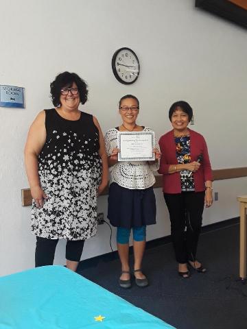 three women, one holding certificate